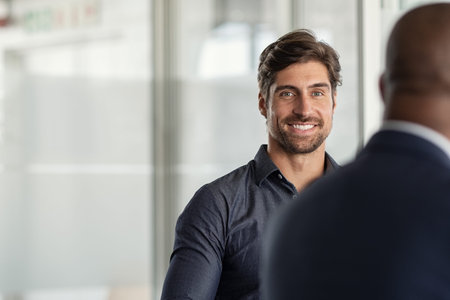 Portrait of successful young businessman in modern office looking at camera with copy space....