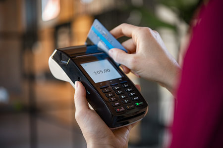 Close up of woman hands making a credit card payment with card reader machine. Credit card swipe...