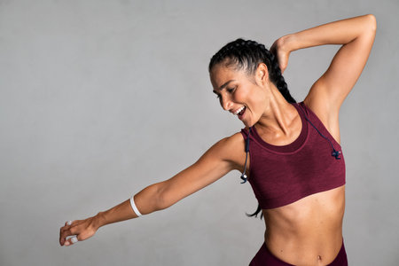 Laughing beautiful woman dancing on gray background. Latin mid adult woman smiling and relaxing...