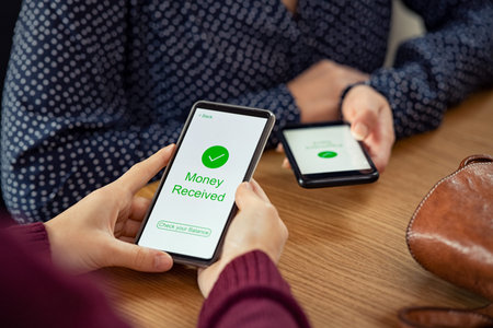 Close up of woman hands holding mobile phone with application to receive money. People holding smart...