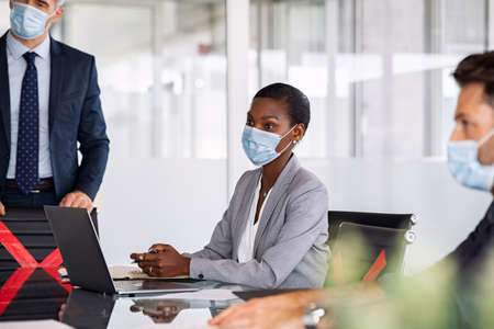 Group of businessmen and businesswomen in conference room in a meeting while keeping social distancing during  pandemic.の写真素材