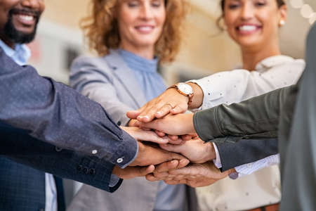 Close up of multiethnic business people stacking hands in modern office. Successful business team stacking hands each other. Detail of young and mature office colleague joining together.の写真素材