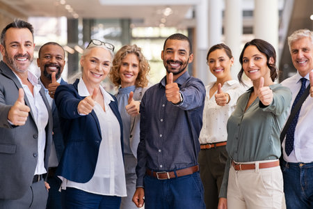 Group of happy multiethnic business people showing sign of success. Successful business team showing thumbs up and looking at camera. Portrait of smiling businessmen and businesswomen cheering at office.の写真素材