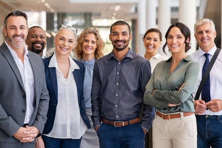 Portrait of successful group of business people at modern office looking at camera. Portrait of happy businessmen and satisfied businesswomen standing as a team. Multiethnic group of people smiling and looking at camera.の写真素材