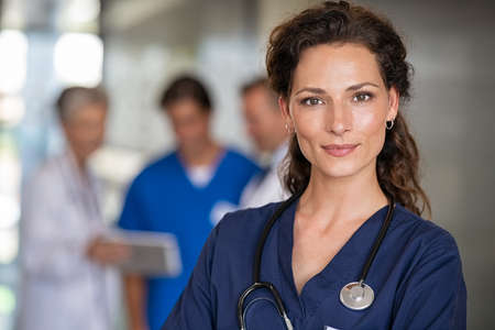 Portrait of proud female nurse with stethoscope around neck at medical clinic. Happy smiling young woman doctor at hospital lobby with copy space. Medical staff feeling confident after a major operation and looking at camera.の写真素材