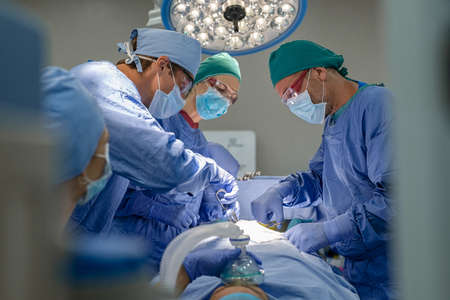 Medical team performing surgical operation in modern operating room. Surgery staff operating in a surgical room at hospital. Concentrated surgeons working on patient in an operation theater.の写真素材