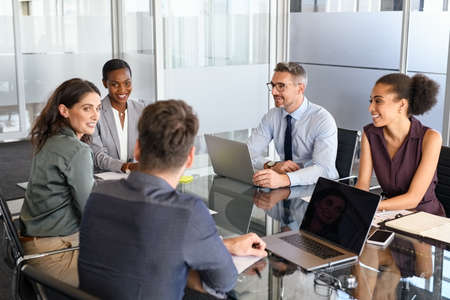 Group of business people have a discussion in conference room. Formal business team brainstorming over new project. Mature businessman and businesswoman talking and working  while sitting in modern conference room with business partners.の写真素材