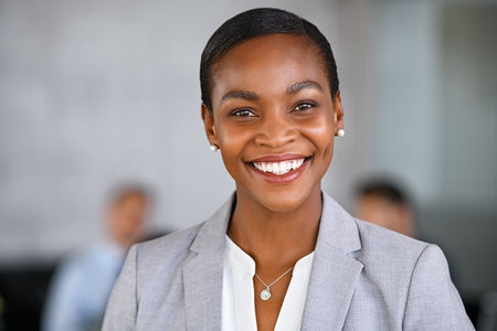 Portrait of mature beautiful black businesswoman looking at camera. Successful african american woman standing in office with satisfaction. Confident and proud woman entrepreneur smiling with copy space at conference room.の写真素材