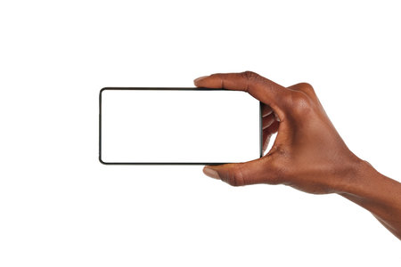 Close up of african american woman hand showing smartphone against white background horizontally. Black woman holding with one hand cellphone with empty screen. Closeup of mobile phone with blank screen isolated on white background.の写真素材