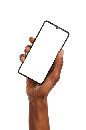 Close up of black woman hand holding smartphone against white background. African american woman hand holding cellphone while showing empty screen isolated. Closeup of female raising up hand while holding cell phone vertically with blank screen ready for your website.の写真素材