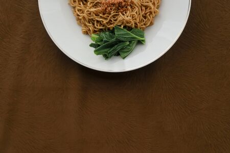Tasty Fried noodle (Indomie Goreng) with sunny side up egg, and vegetable. served on white plate. Top view close up detailの写真素材