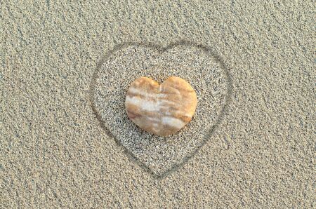 Heart shaped pebble on the sand beachの写真素材