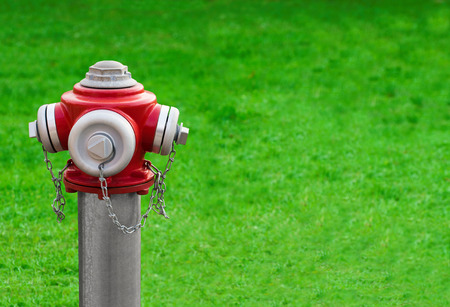 Modern red hydrant on a green grass background with space for textの写真素材