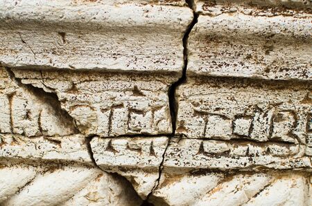 Ancient stone wall with inscriptions damaged by forces of nature for a long period of timeの写真素材