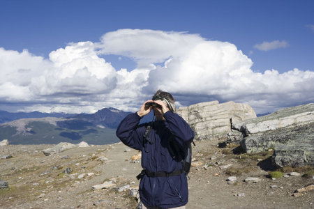 mountain hiker looking through binoculars - mount whistler, jasper national park, canadaの写真素材