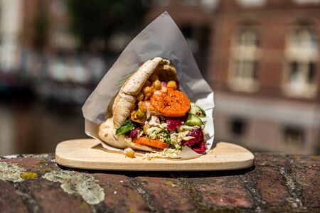 lovely falafel pita on a wooden plate outside on a brick wallの写真素材
