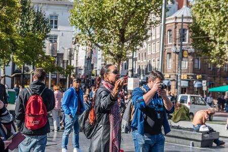 Amsterdam, Holland, September 2018 too many tourists visiting the city of Amsterdam proofs this long female guide with red umbrella and long leather jacket and sunglassesのeditorial素材
