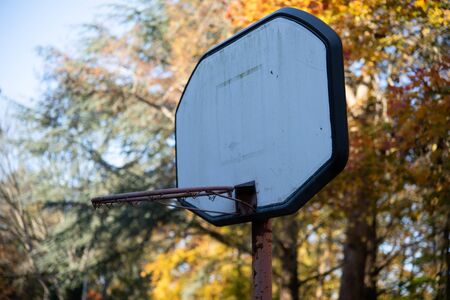 worn out basketball hoop in the woodland against leafs and blue sky backgroundの写真素材