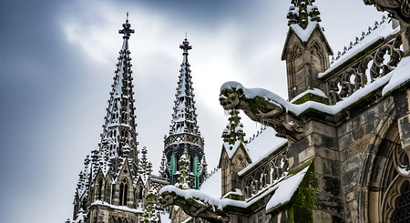 Snow covered gothic cathedral with gargoyles in detailed architecture. Dramatic winter scene with cloudy sky for background apparent.の素材