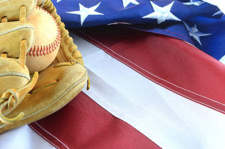Closeup of worn baseball and mitt on a US flag background, great for Americas favorite pasttime. Copy space.の写真素材