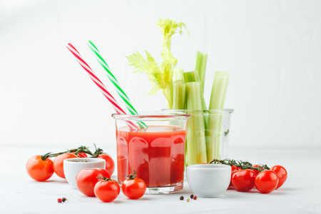 Tomato juice with celery and spices on a white wooden backgroundの写真素材