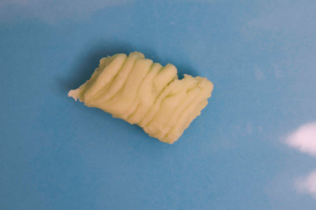 A piece of potato on a blue background. Close-up.