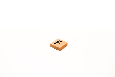 Wooden tile with letter F on white background, isolated close-up photo