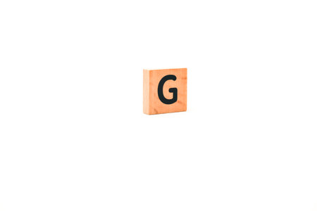 Single wooden block with letter G on white background isolated