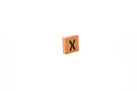 Wooden block with the letter X on a white background for educational alphabet learning games