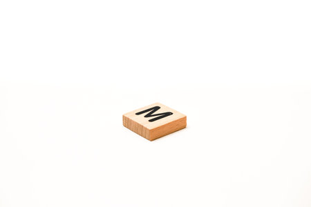 Isolated wooden tile with the letter M, perfect for educational materials and graphic design...