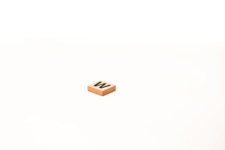 Isolated shot of a wooden block displaying the letter W on a stark white background