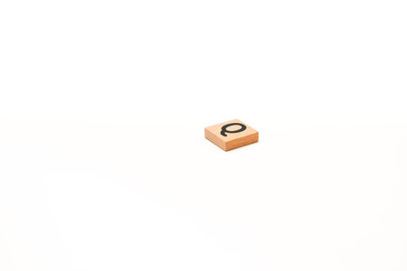 A wooden tile with the letter Q isolated on a white background, suitable for educational useの写真素材