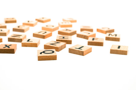 A set of wooden alphabet blocks scattered randomly on a clean white background