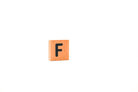 Isolated shot of a wooden alphabet block with the letter F in black on a white backgroundの写真素材