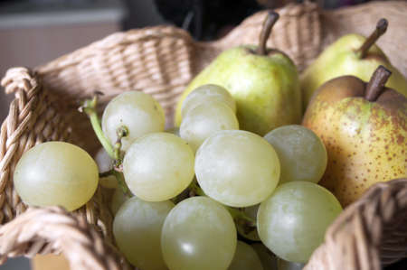 Green yellow grapes in a basket with pearsの写真素材