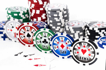 Piled colored chips with four aces isolated on white background