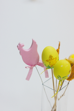 Easter decoration with a rabbit, eggs and flowers in a glass vase on a white backgroundの写真素材