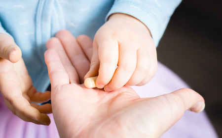 Baby hand taking a pill from adults handの写真素材