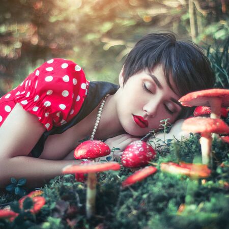 Beautiful young girl in forest with mushroomsの写真素材