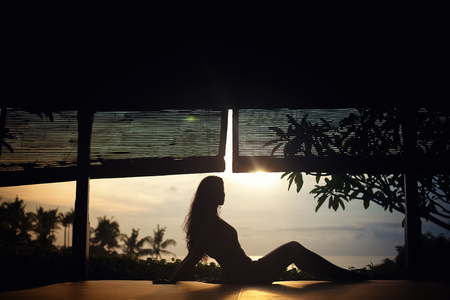 Sexy woman on sailboat lying down on the deck of luxury sailboat, tanning on mild sunset light, enjoying sea cruise, fashion and summer holidays conceptの写真素材