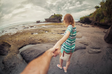 Woman walking on the beach take handの写真素材