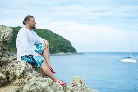 Young man having pleasure sitting on the rockssの写真素材