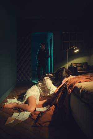 Unhappy woman in bed and a man in the backgroundの写真素材