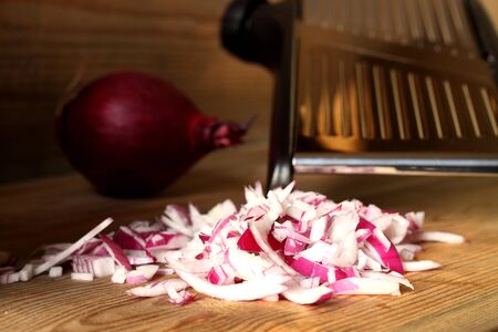 Chopped red onion with mandolin on wooden backgroundの写真素材