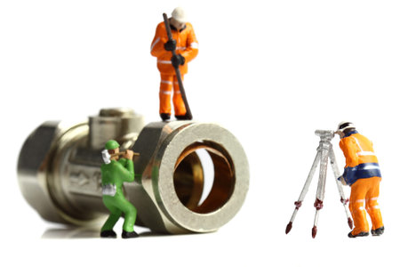 Isolated miniature scale model construction workers with a plumbing valve