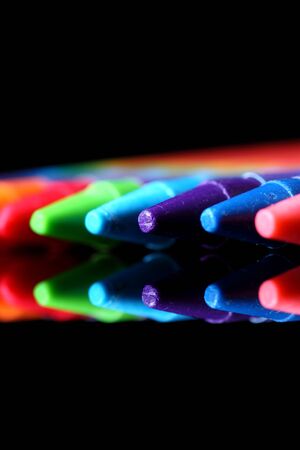 Colored wax crayons in a row reflected against black backgroundの写真素材