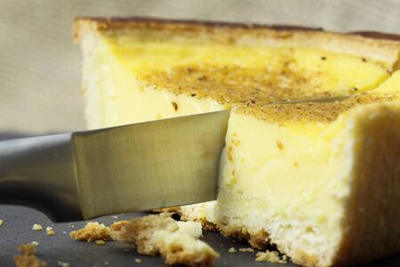 Slicing a custard tart on a slate backgroundの写真素材