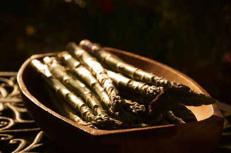 Freshly picked asparagus in a wooden dish on a garden table outdoorsの写真素材