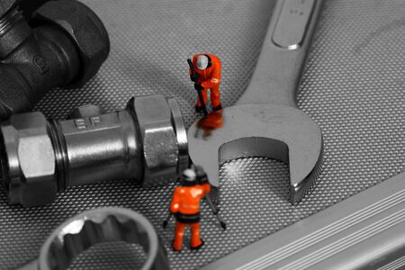 Scale model construction workers standing on a tool box with spanners and plumbing valvesの写真素材
