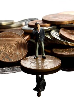 Miniature business figure standing on British coins.の写真素材